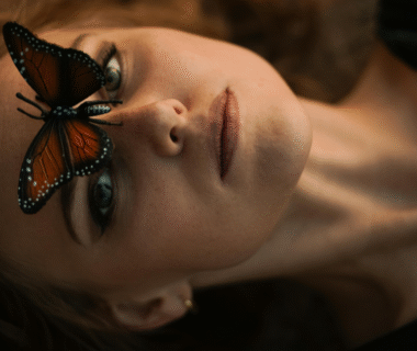 Woman lying peacefully with a butterfly on her forehead, symbolizing personal transformation and awakening.