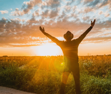 A man standing with arms raised greeting the sunrise, symbolizing spiritual awakening, inner peace, and personal transformation.