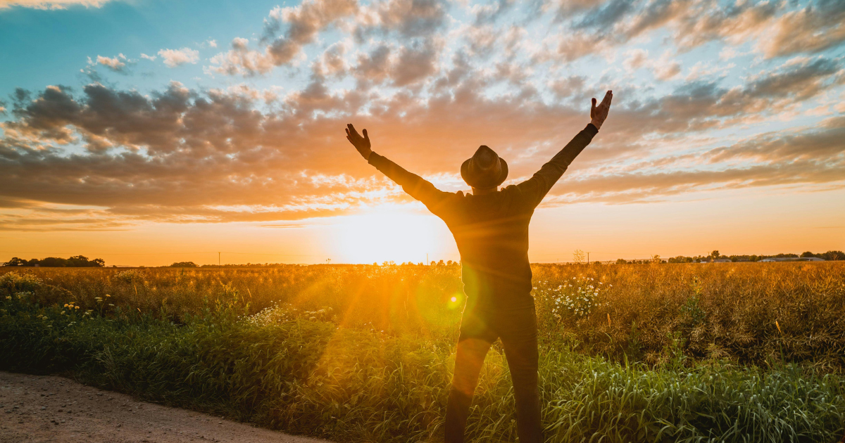 A man standing with arms raised greeting the sunrise, symbolizing spiritual awakening, inner peace, and personal transformation.
